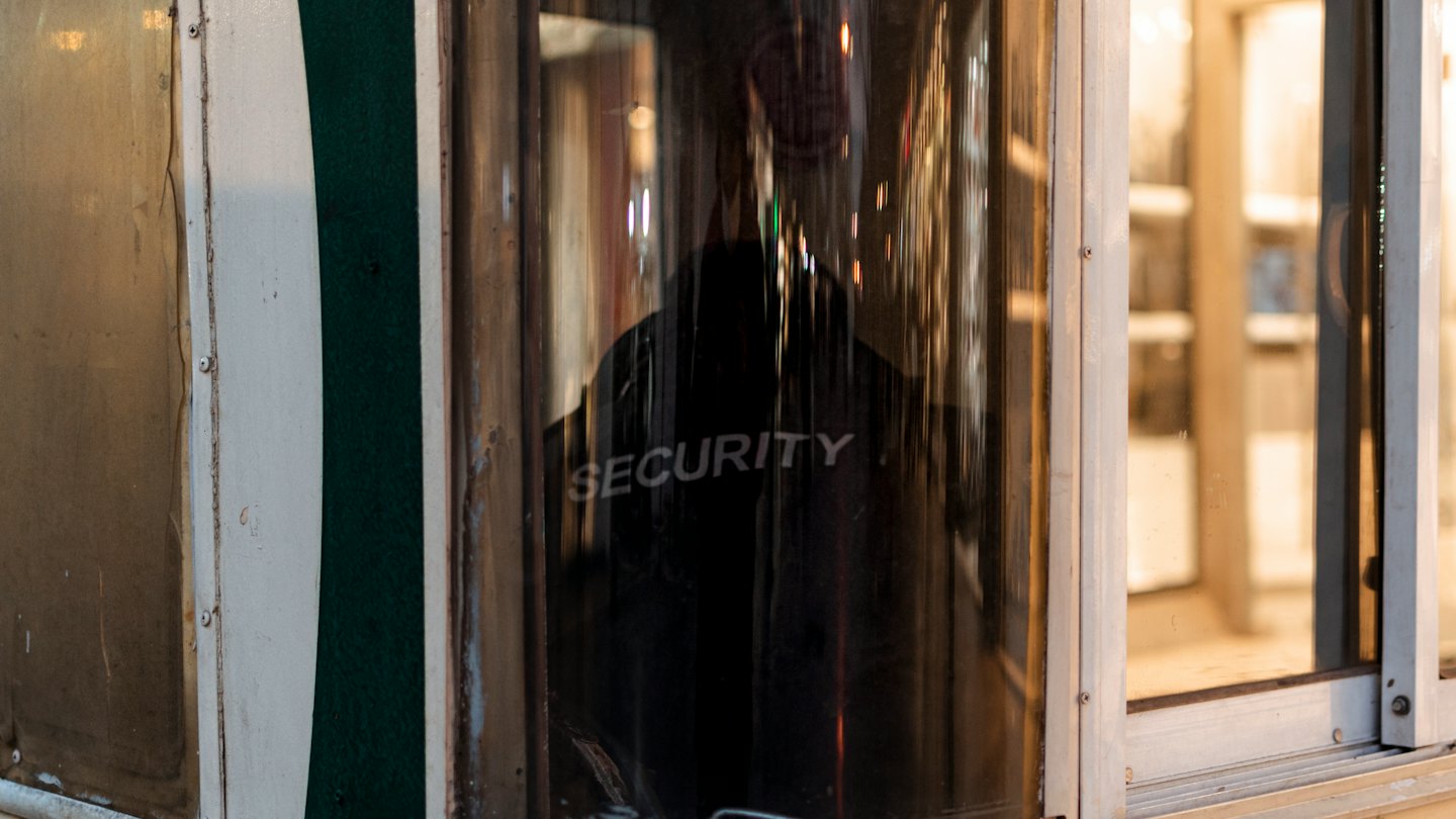 Un agent de sécurité en uniforme se tient à l'intérieur d'une petite guérite.